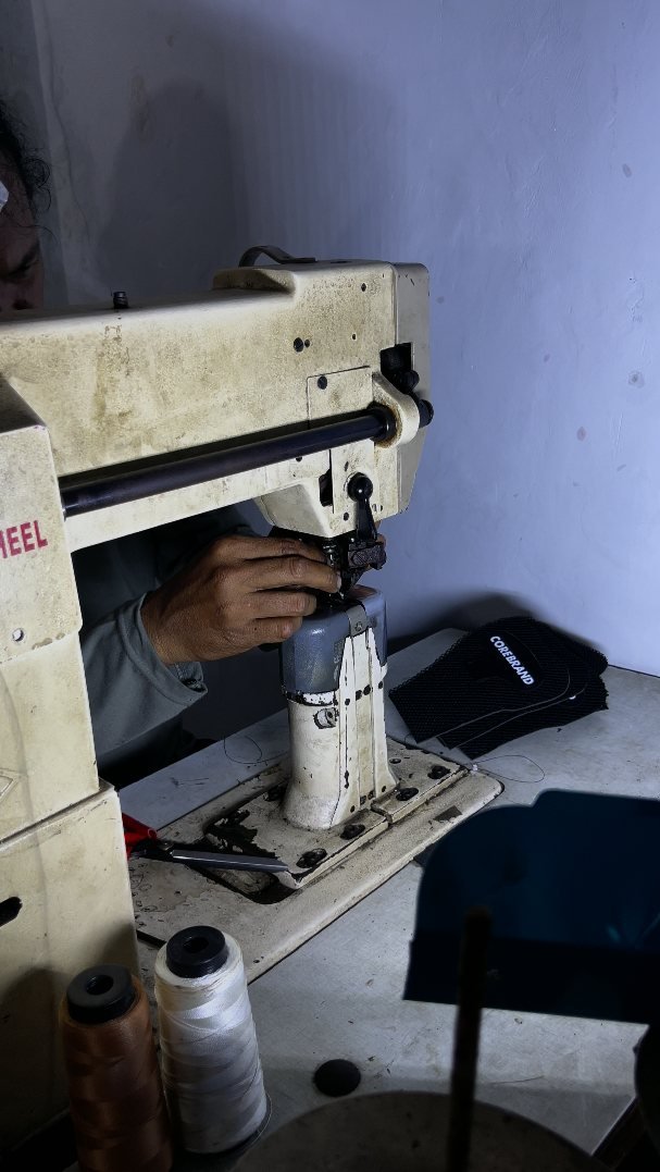 Mesin jahit industri khusus sepatu sedang menjahit bagian atas sepatu